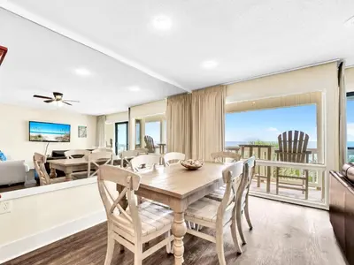 a dining room with a table and chairs and a balcony at Latitude 29 #36 in Panama City Beach