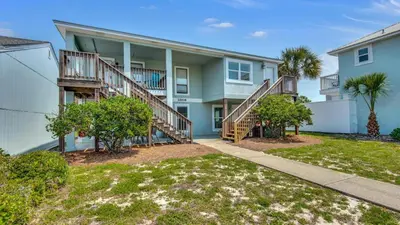 an exterior view of a house with stairs and trees at Bahama West by Panhandle Getaways in Panama City Beach