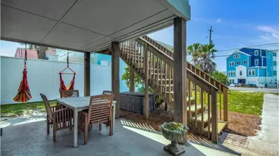 a patio with a table and chairs and a staircase at Bahama West by Panhandle Getaways in Panama City Beach