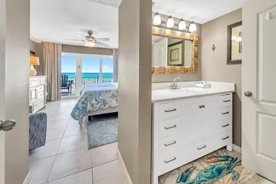 a bathroom with a sink and a mirror and a bedroom at Dunes of Panama 205D in Panama City Beach