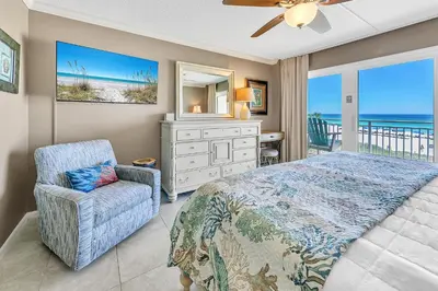 a bedroom with a bed and a chair and a dresser at Dunes of Panama 205D in Panama City Beach