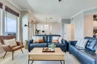 a living room with a blue couch and a table at Newly Renovated Luxury OCEAN FRONT Condo! Top Floor Condo with PENTHOUSE OCEAN VIEWS! in Panama City Beach