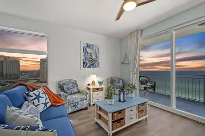 a living room with a blue couch and a large window at Coral Charm in Panama City Beach