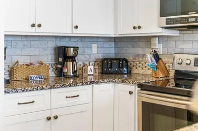 a kitchen with white cabinets and a counter top at Coral Charm in Panama City Beach