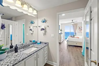 a bathroom with two sinks and a bedroom with a bed at Coral Charm in Panama City Beach