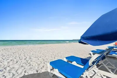 a pair of blue chairs and an umbrella on a beach at Coral Charm in Panama City Beach