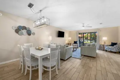 a dining room and living room with a white table and chairs at Gulf Highlands #175 by Nautical Properties in Panama City Beach