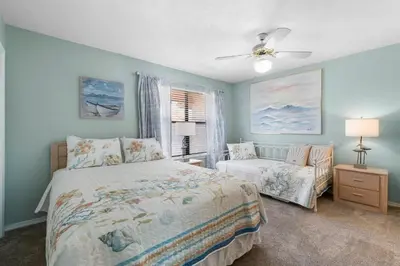 a bedroom with a bed and a chair in it at Gulf Highlands #175 by Nautical Properties in Panama City Beach