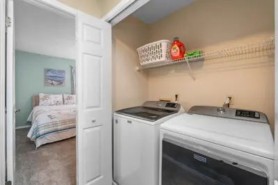 a laundry room with a washing machine and a bed at Gulf Highlands #175 by Nautical Properties in Panama City Beach
