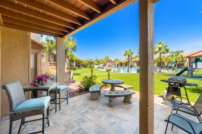 a patio with tables and chairs and a grill at Gulf Highlands #175 by Nautical Properties in Panama City Beach