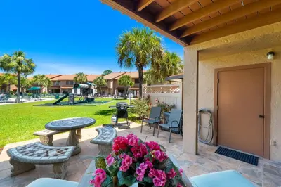 a patio with a table and chairs and flowers at Gulf Highlands #175 by Nautical Properties in Panama City Beach