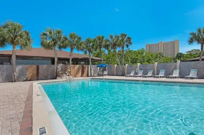 a large swimming pool with palm trees and chairs at Portside P1 in Panama City Beach