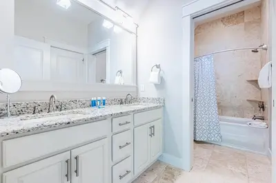 a white bathroom with two sinks and a shower at Plimsoll Retreat at Watersound West Beach in Santa Rosa Beach
