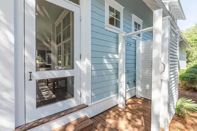 a front door of a blue house with a patio at Plimsoll Retreat at Watersound West Beach in Santa Rosa Beach