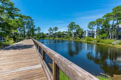 a wooden bridge over a river with trees at Plimsoll Retreat at Watersound West Beach in Santa Rosa Beach