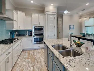 a kitchen with white cabinets and a stainless steel sink at Prominence North #54A - Barefoot Bungalow in Inlet Beach