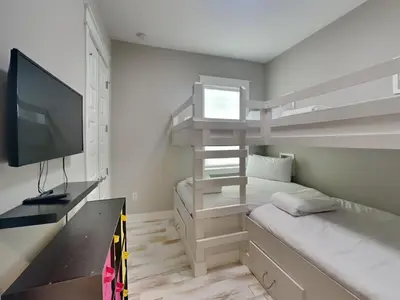 a small bedroom with a bunk bed and a television at Prominence North #54A - Barefoot Bungalow in Inlet Beach