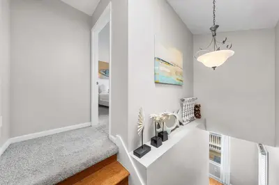 a hallway with white walls and a staircase with a chandelier at Serenity - Inlet Beach in Inlet Beach