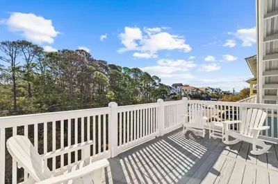 a balcony with two white chairs on a white fence at Sea Power in Santa Rosa Beach