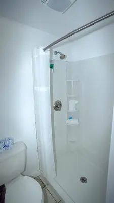 a white bathroom with a shower and a toilet at Banana Peel Lodge in Panama City Beach