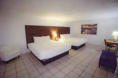 a hotel room with two beds and a desk and chair at Banana Peel Lodge in Panama City Beach
