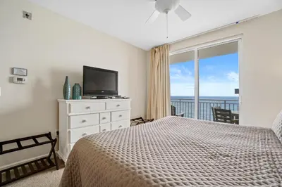 a bedroom with a bed and a television and a balcony at 607-E-Splash in Panama City Beach