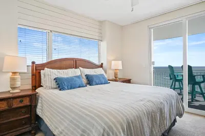 a bedroom with a bed with blue pillows and a balcony at 607-E-Splash in Panama City Beach