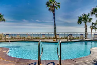 a large swimming pool with palm trees and the ocean at 607-E-Splash in Panama City Beach