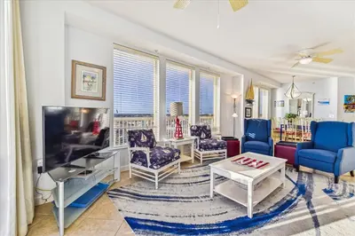 a living room with blue chairs and a flat screen tv at 909-Seychelles in Panama City Beach