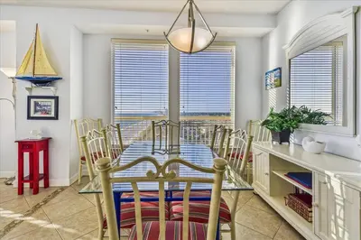a dining room with a glass table and chairs at 909-Seychelles in Panama City Beach
