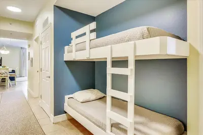 a white bunk bed in a room with a blue wall at 804-Tidewater in Panama City Beach