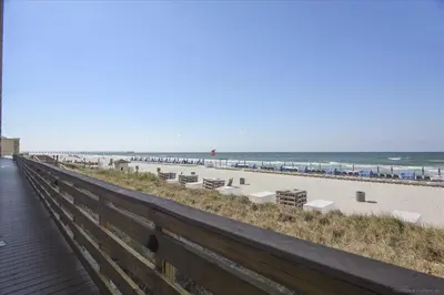 a boardwalk leading to a beach with chairs and the ocean at 804-Tidewater in Panama City Beach