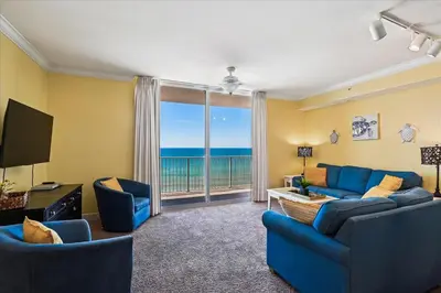 a living room with blue furniture and a large window at 804-Tidewater in Panama City Beach