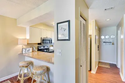 a kitchen with a counter and two bar stools at Breezy PCB Retreat with Balcony - Walk to Beach! in Panama City Beach