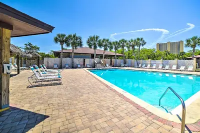 a swimming pool with lounge chairs and a resort at Breezy PCB Retreat with Balcony - Walk to Beach! in Panama City Beach