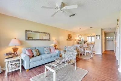 a living room with a blue couch and a table at Breezy PCB Retreat with Balcony - Walk to Beach! in Panama City Beach