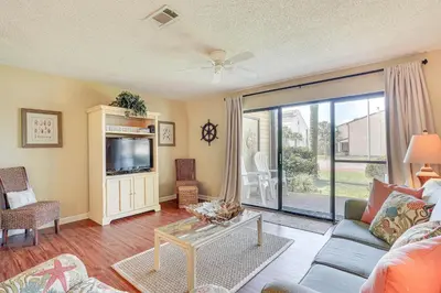 a living room with a couch and a tv at Breezy PCB Retreat with Balcony - Walk to Beach! in Panama City Beach