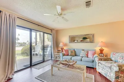 a living room with a couch and a table at Breezy PCB Retreat with Balcony - Walk to Beach! in Panama City Beach