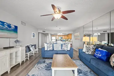 a living room with a blue couch and a ceiling fan at Watercrest 906 | Sand, Sea & Serenity in Panama City Beach