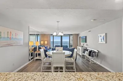 a dining room and living room with a table and chairs at Watercrest 906 | Sand, Sea & Serenity in Panama City Beach
