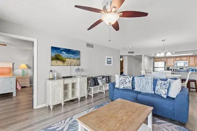 a living room with a blue couch and a ceiling fan at Watercrest 906 | Sand, Sea & Serenity in Panama City Beach