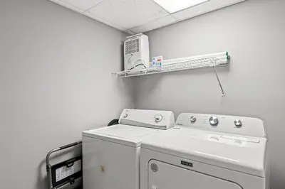 a laundry room with a washing machine and a shelf at Watercrest 906 | Sand, Sea & Serenity in Panama City Beach