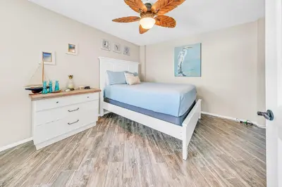 a bedroom with a white bed and a dresser at Dunes of Panama 2104E in Panama City Beach