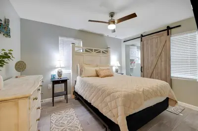 a bedroom with a large bed and a dresser with a ceiling fan at Sea Breeze House- 3 bd 2 ba 5 min walk to beach in Panama City Beach