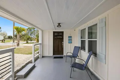 a porch with two chairs and a door at Sea Breeze House- 3 bd 2 ba 5 min walk to beach in Panama City Beach