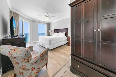 a bedroom with a bed and a dresser and a chair at Grandview East 1201 in Panama City Beach