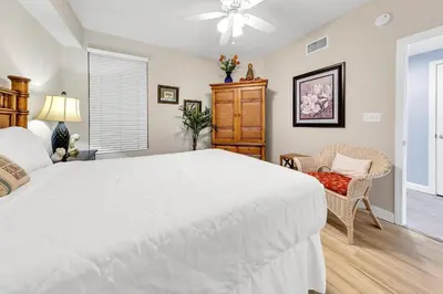 a bedroom with a large white bed and a chair at Grandview East 1201 in Panama City Beach