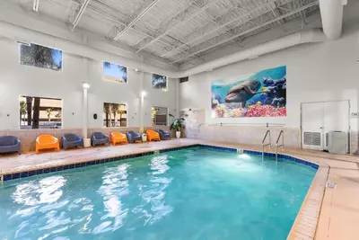 a swimming pool with orange chairs and a painting on the wall at Tidewater 2604 - SunBeam Dreams in Panama City Beach