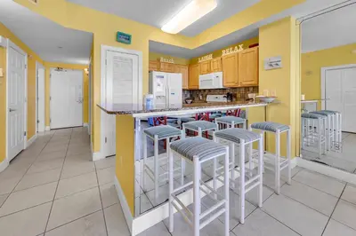 a kitchen with yellow walls and bar stools at Sunrise Beach #2107 in Panama City Beach