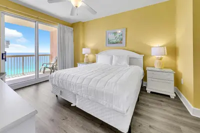 a bedroom with a white bed and a balcony at Sunrise Beach #2107 in Panama City Beach